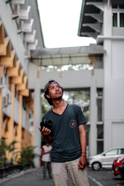身穿灰色V领衬衫的男子站在人行道上